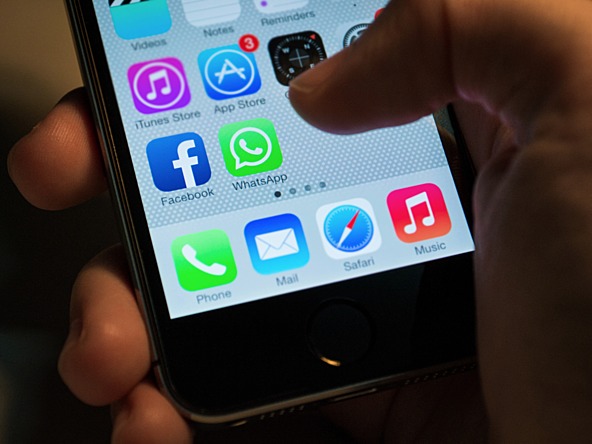 hand holding a smartphone with thumb hovering near whatsapp icon